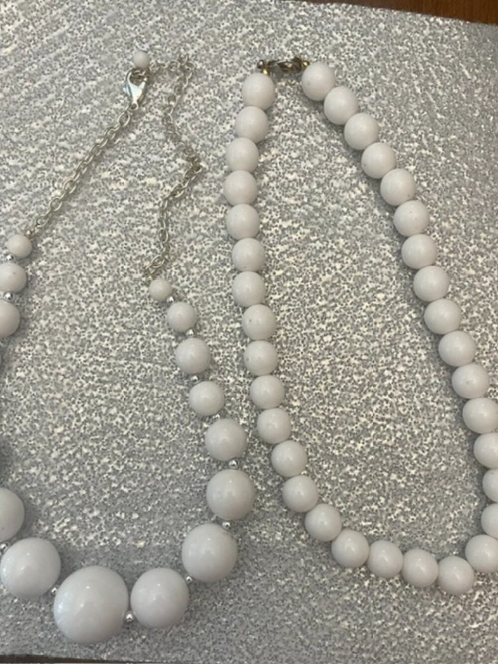Two white bead necklaces with a graduated size design and silver-tone accents.